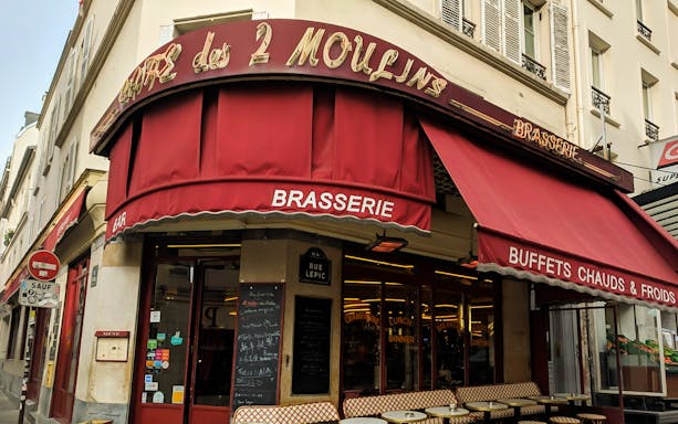 Cafe des 2 Moulins exterior with red awning on Rue Lepic, Paris.