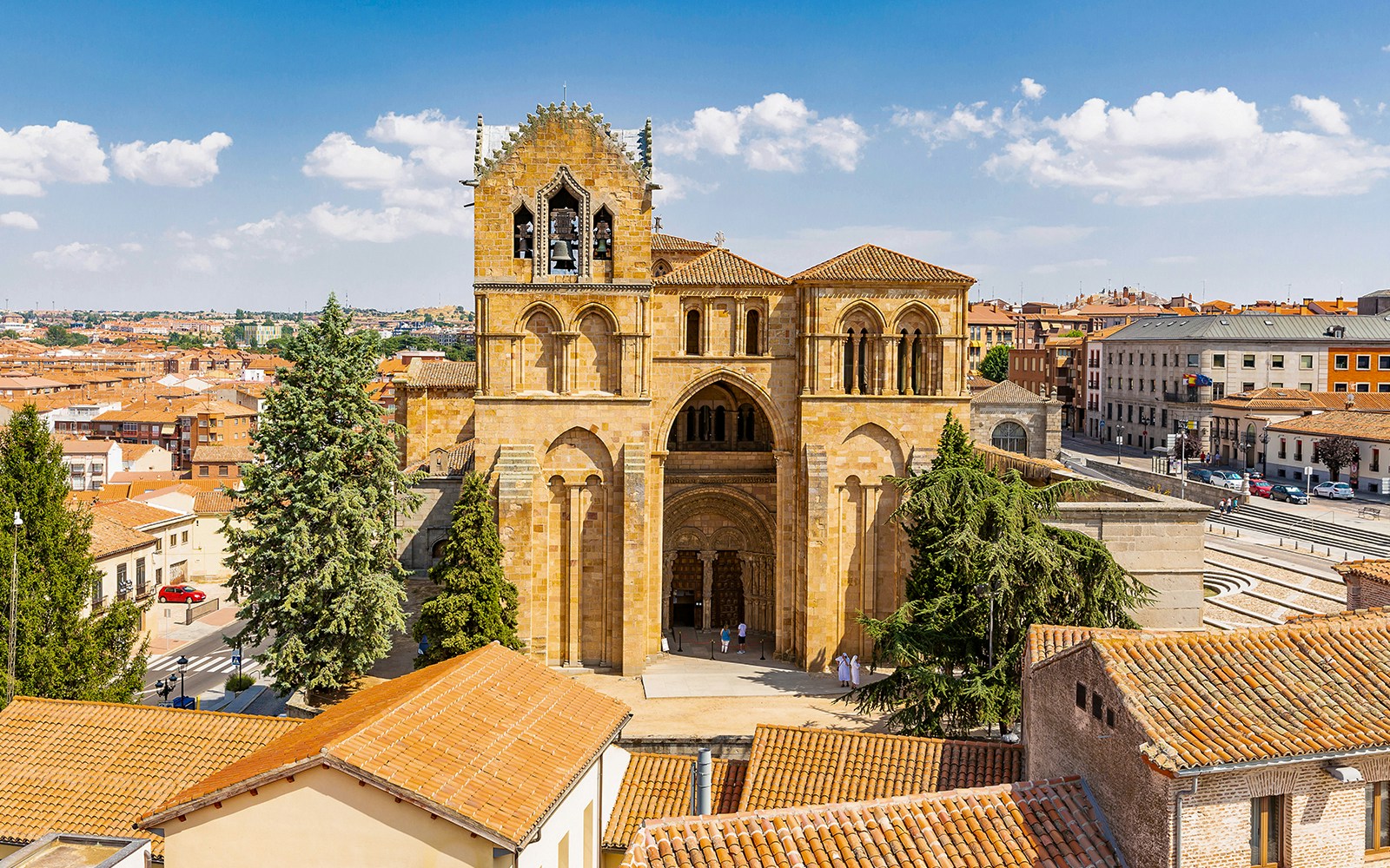 Avila cityscape with San Vicente Basilica in foreground, showcasing historic architecture and surrounding landscape.