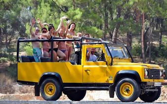 Group enjoying Alanya day-trip in open-top yellow jeep through forest.