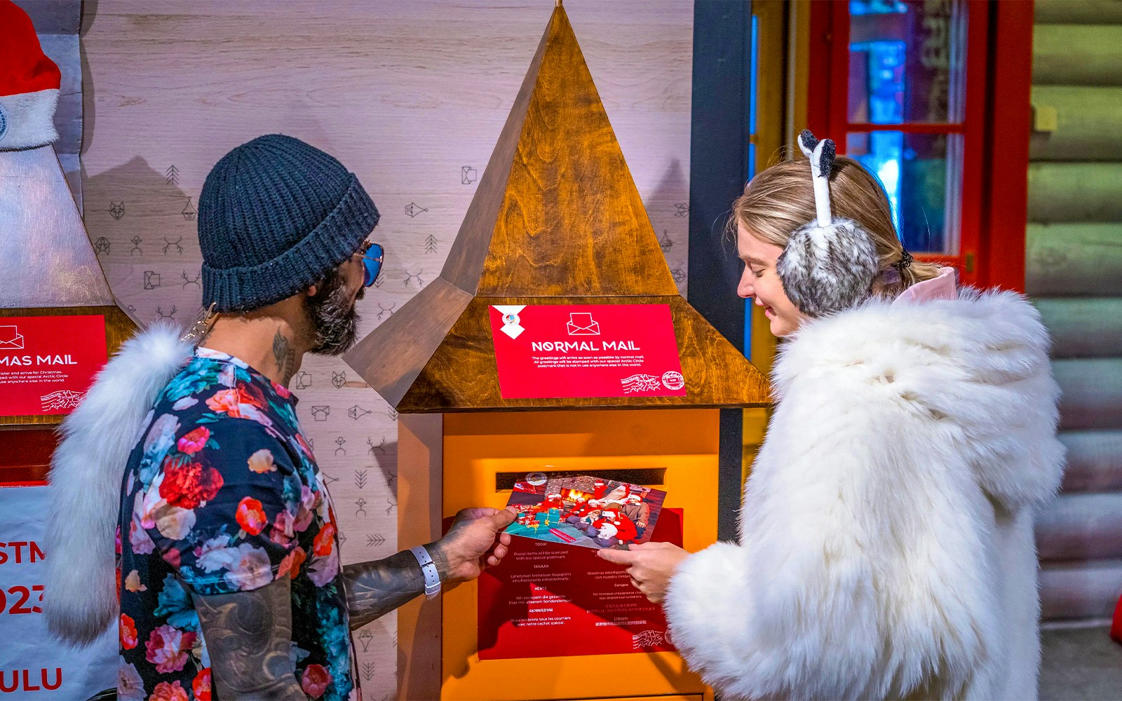 Guests at Santa Claus Village Rovaniemi sending postcards in festive setting.