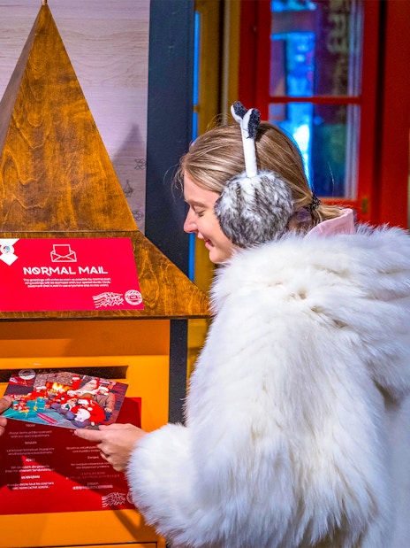 Guests at Santa Claus Village Rovaniemi sending postcards in festive setting.