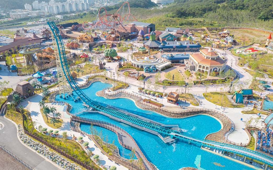 Aerial view of Lotte World Adventure Busan with roller coasters and water attractions.