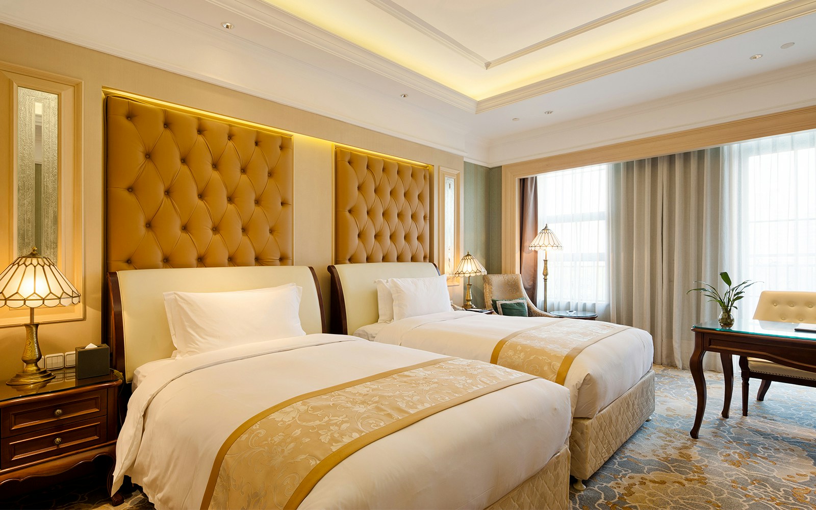 Hotel room with a bed, desk, and window in a generic setting.