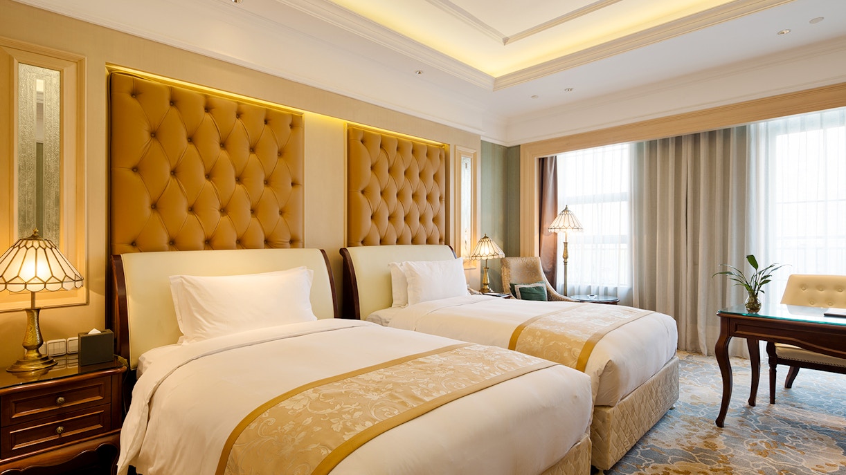 Hotel room with a bed, desk, and window in a generic setting.