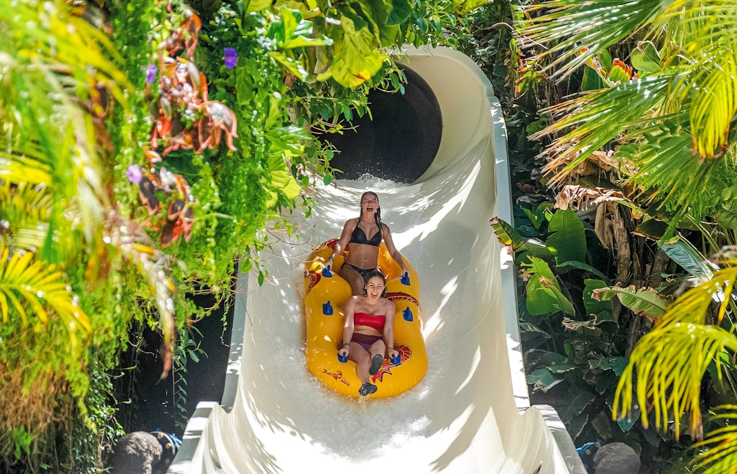 Group of excited tourists enjoying a thrilling water slide ride with Skip-the-Line Tickets at Siam Park, Tenerife