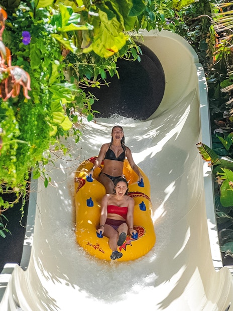 Visitors enjoying a water slide at Siam Park, surrounded by lush greenery.