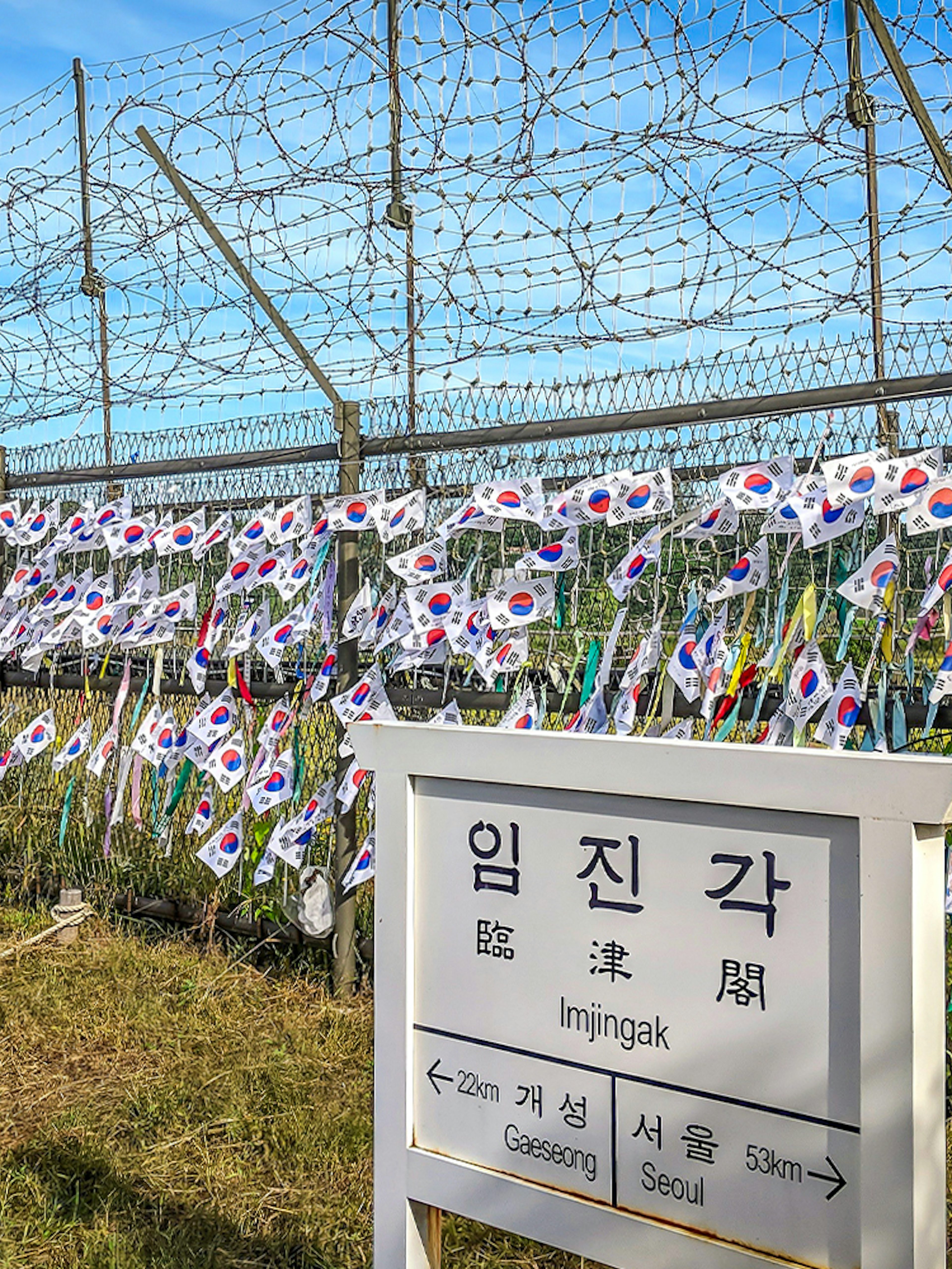 Imjingak sign and barbed wire fence with Korean flags at the DMZ.