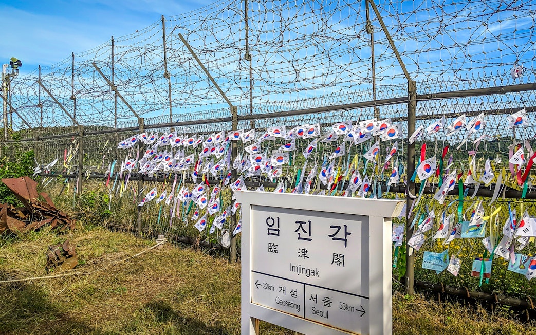Imjingak sign and barbed wire fence with Korean flags at the DMZ.
