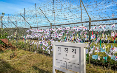 Imjingak sign and barbed wire fence with Korean flags at the DMZ.