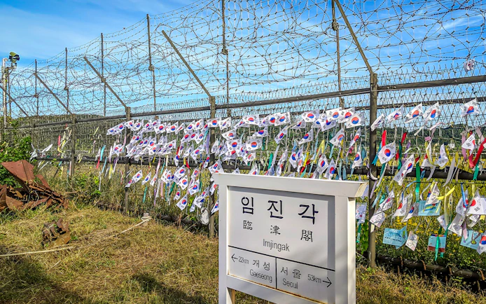 Imjingak sign and barbed wire fence with Korean flags at the DMZ.