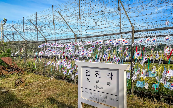 Imjingak sign and barbed wire fence with Korean flags at the DMZ.