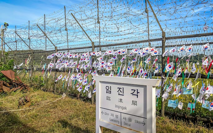 Imjingak sign and barbed wire fence with Korean flags at the DMZ.