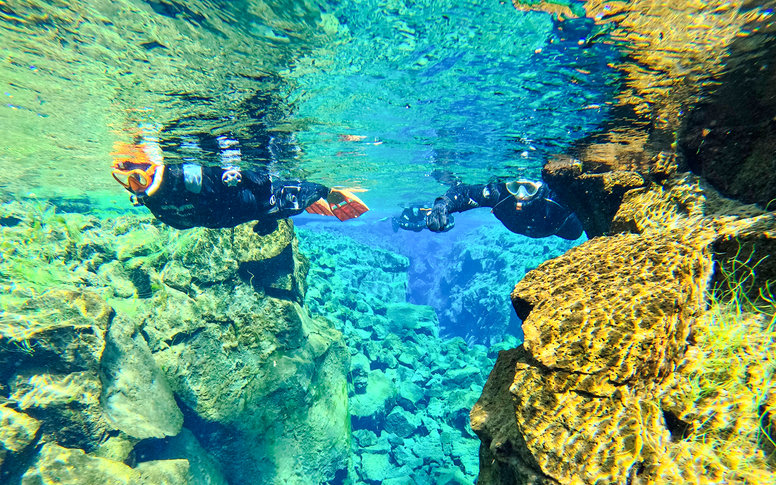Snorkelers exploring clear waters and rock formations in Silfra, Iceland.