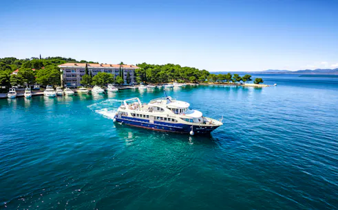 Boat cruising near Brijuni National Park with coastal buildings and trees in Fažana, Croatia.