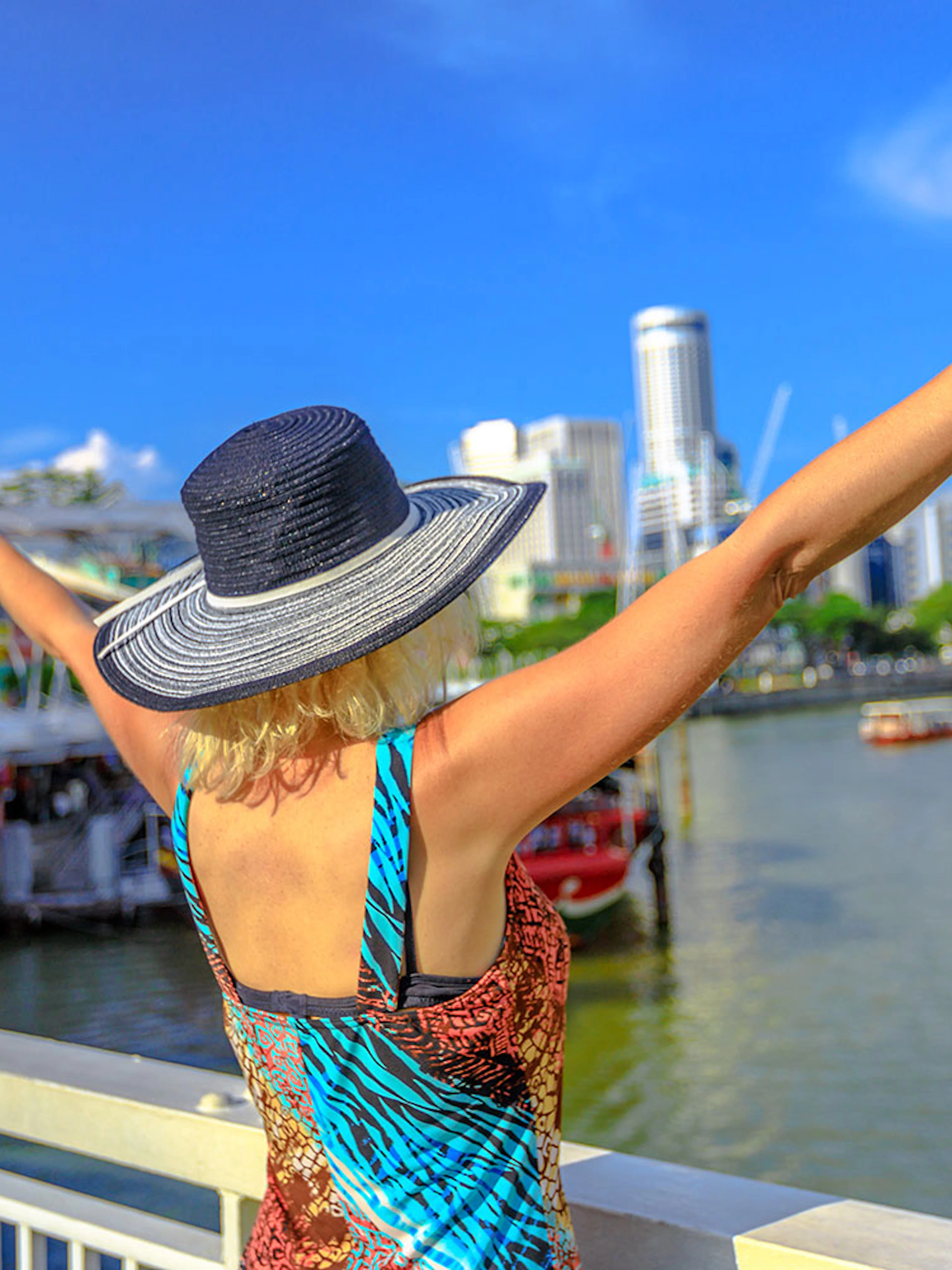 Boat cruising on Singapore River with city skyline and historic bridges in view.