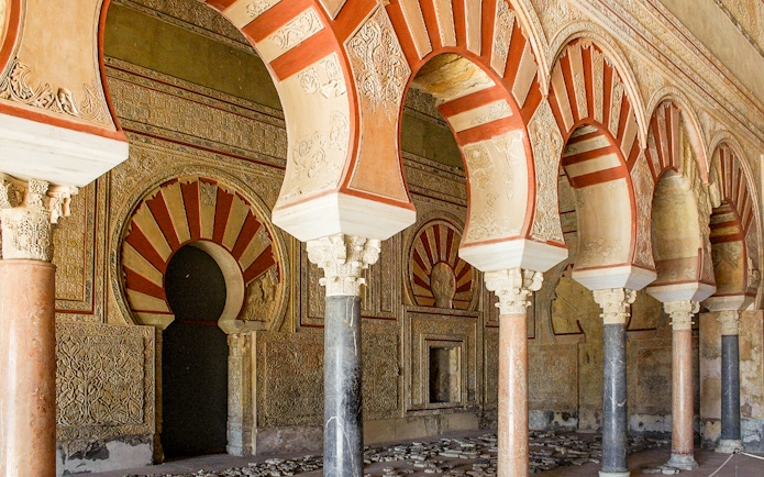 Arched pillars and intricate carvings at Medina Azahara archaeological site in Córdoba, Spain.