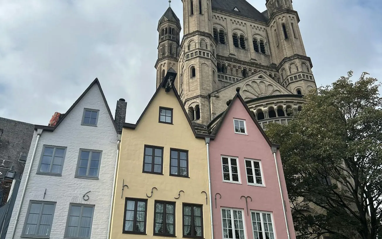 Colorful houses and Great St. Martin Church in Cologne, part of the self-guided city exploration game.