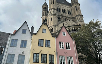 Colorful houses and Great St. Martin Church in Cologne, part of the self-guided city exploration game.