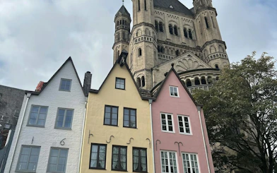 Colorful houses and Great St. Martin Church in Cologne, part of the self-guided city exploration game.