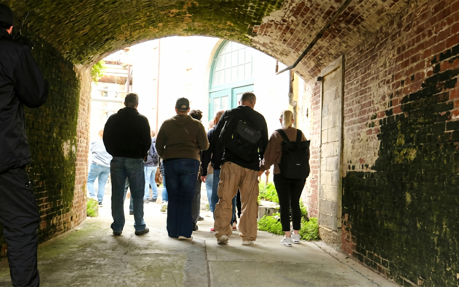 Visitors walking through a brick tunnel on a behind-the-scenes tour of Alcatraz Island.
