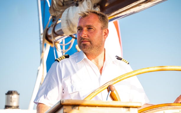 Captain steering a boat on an Amsterdam Skyline Tour.