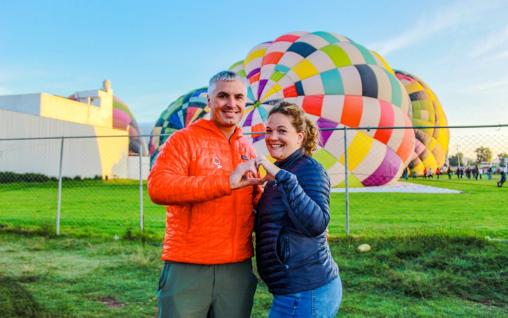 Couple posing in front of colorful hot air balloons at Teotihuacan.