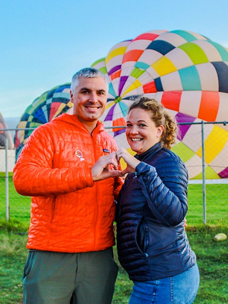 Couple posing in front of colorful hot air balloons at Teotihuacan.