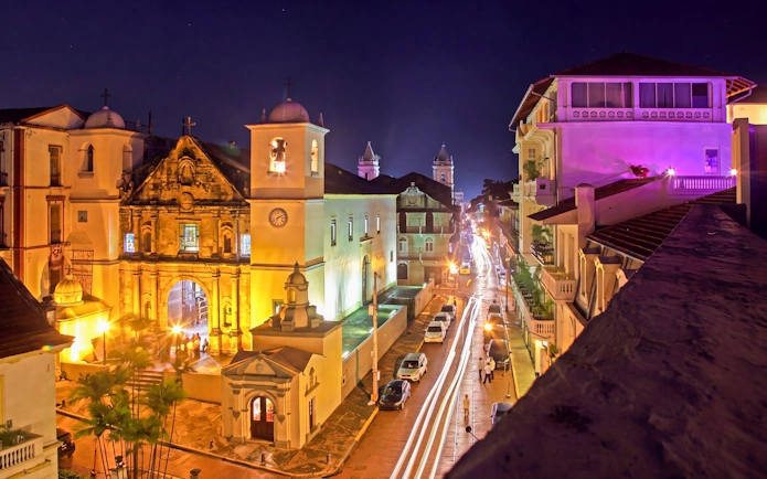 Casco Viejo at night with illuminated colonial architecture and bustling street in Panama City.