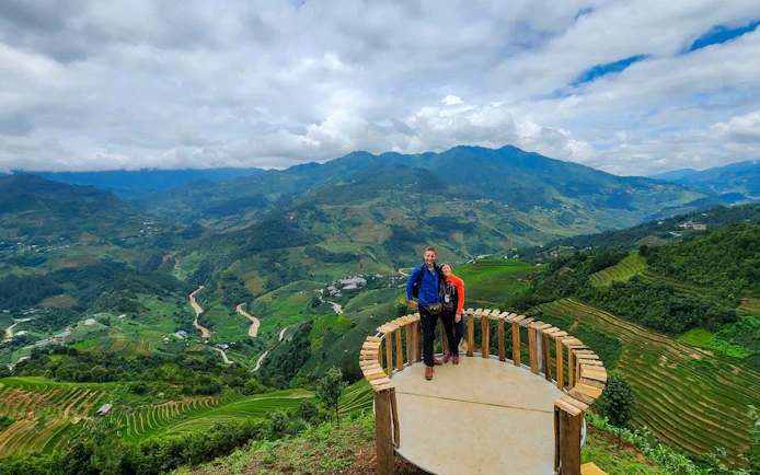 Tourists on a viewing platform overlooking terraced rice fields in Mu Cang Chai, Vietnam.