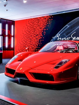 Ferrari Enzo displayed at Ferrari Museum with red and black backdrop.