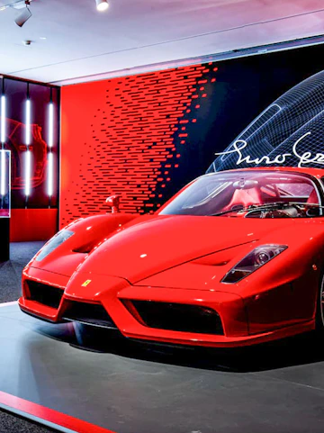 Ferrari Enzo displayed at Ferrari Museum with red and black backdrop.