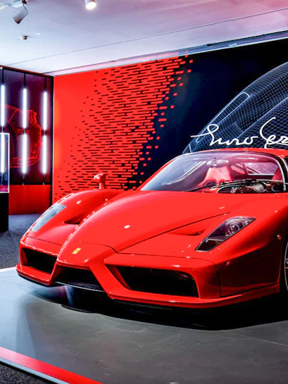 Ferrari Enzo displayed at Ferrari Museum with red and black backdrop.