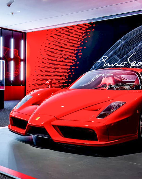 Ferrari Enzo displayed at Ferrari Museum with red and black backdrop.