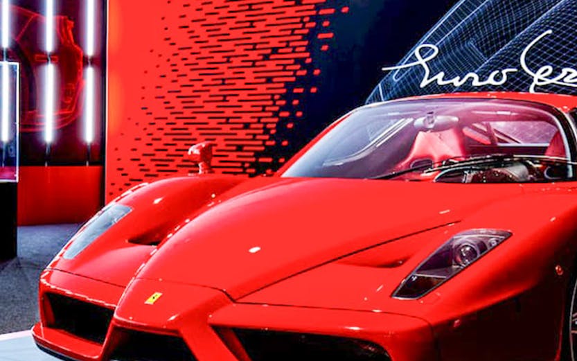 Ferrari Enzo displayed at Ferrari Museum with red and black backdrop.