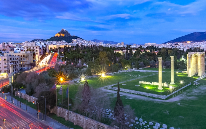 Temple of Olympian Zeus illuminated at night during Athens panoramic tour with open double-decker bus.