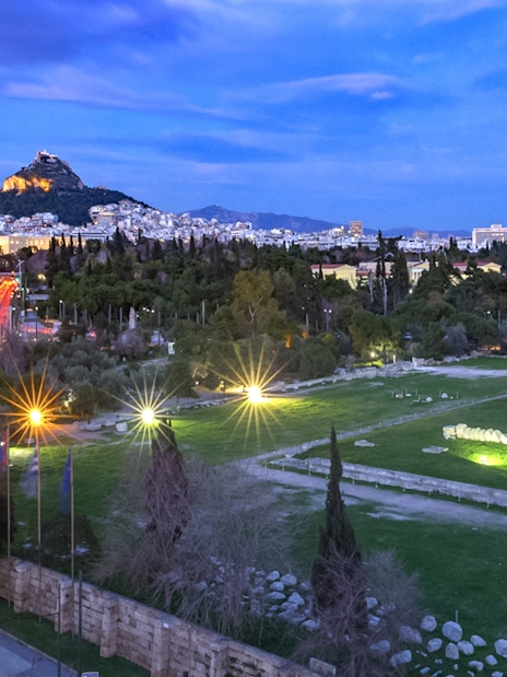 Temple of Olympian Zeus illuminated at night during Athens panoramic tour with open double-decker bus.