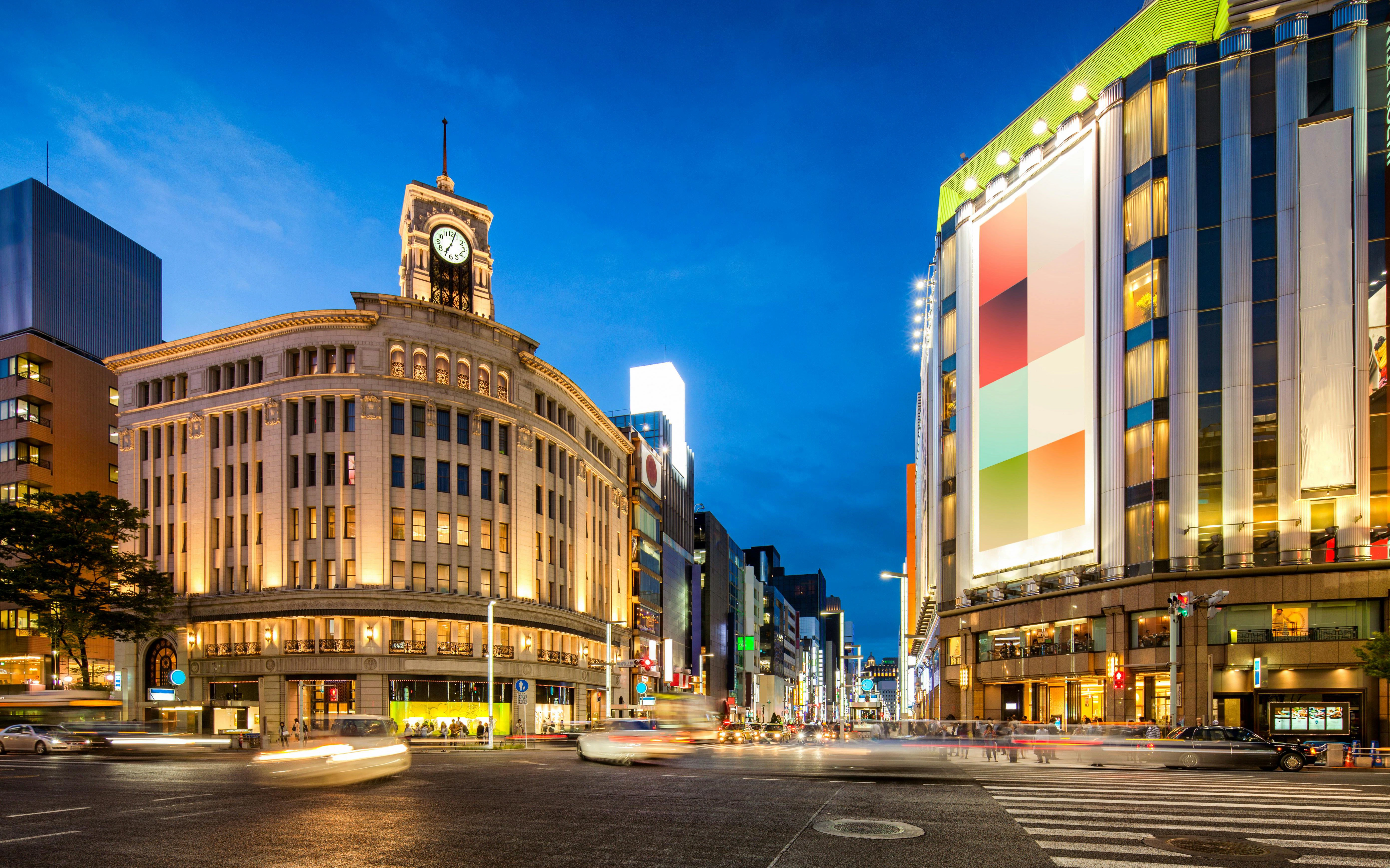 Ginza district at night with illuminated buildings and bustling street in Tokyo, Japan.