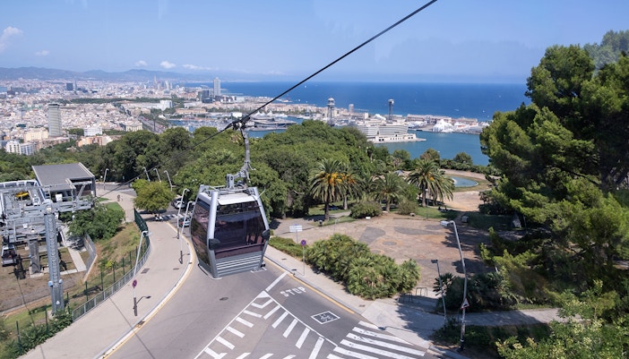 Cable car ascending Montjuic Hill with Sagrada Familia visible in the background, Barcelona.