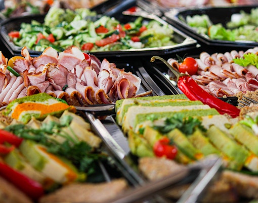 Assorted breakfast platters with meats, salads, and fruits at a spa.