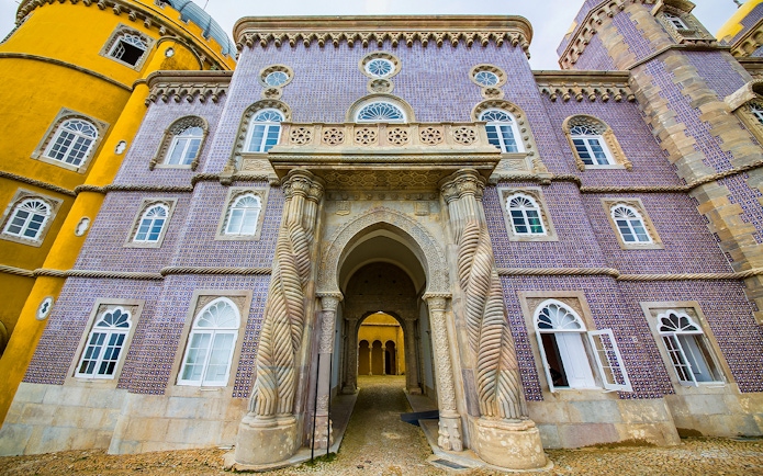 Pena Palace entrance with ornate columns and colorful facade in Sintra, Portugal.