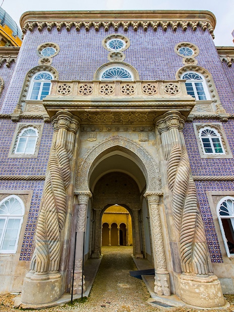 Pena Palace entrance with ornate columns and colorful facade in Sintra, Portugal.