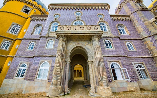 Pena Palace entrance with ornate columns and colorful facade in Sintra, Portugal.