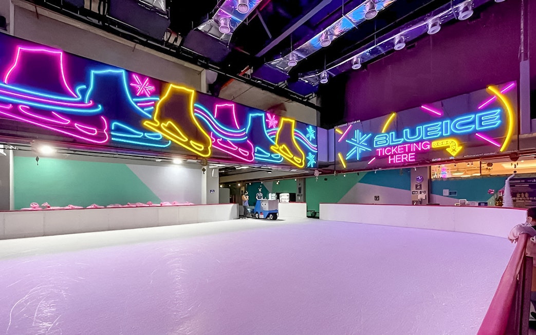 Indoor ice skating rink with neon skate signs at Blue Ice Snow Park, 163 Retail Park.