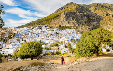 Panorama of Chefchaouen's blue buildings with Rif Mountains in Morocco.