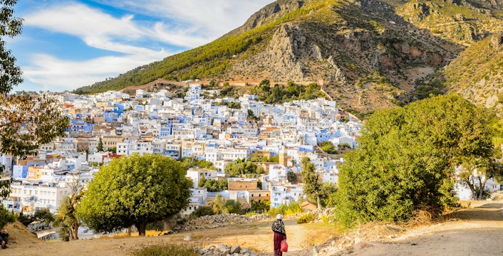 Panorama of Chefchaouen's blue buildings with Rif Mountains in Morocco.