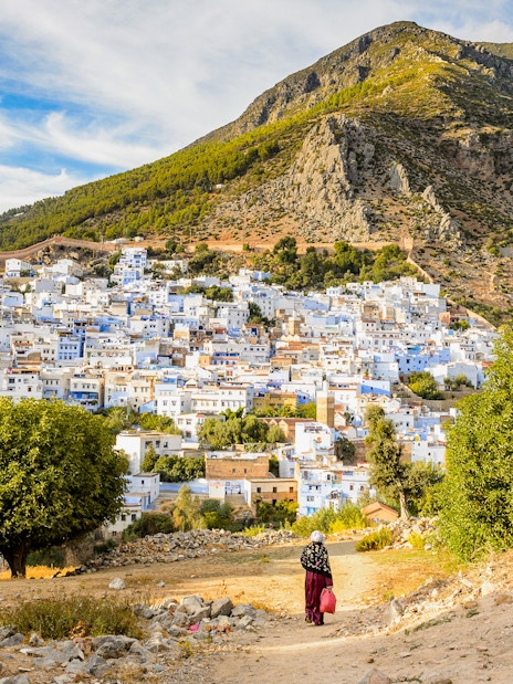 Panorama of Chefchaouen's blue buildings with Rif Mountains in Morocco.