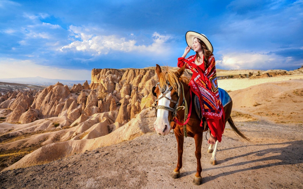 Horseriding in Cappadocia with rock formations in the background.