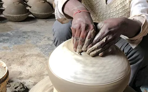 Potter shaping clay on a wheel at a traditional workshop in Al Haouz, Marrakesh.