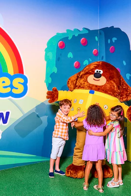 Children hugging a large character at CBeebies Rainbow Adventure.