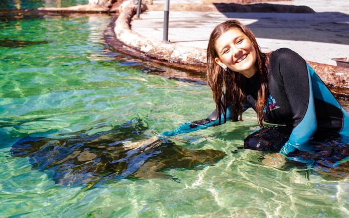 Woman interacting with stingray at Irukandji Shark & Ray Encounters aquarium.